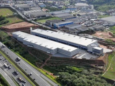 Vista aérea de condomínio de galpões modulares ao lado de rodovia.