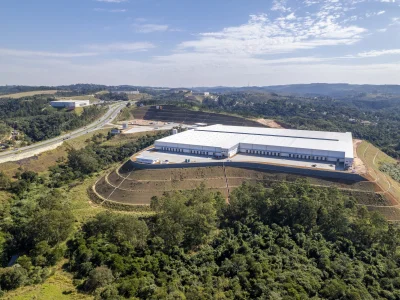 Vista aérea de condomínio de galpões com cé azul no horizonte.