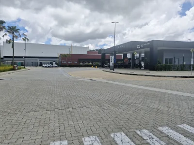 Portaria de condomínio de galpões, com prédios administrativos em segundo plano, e ao fundo céu com núvens.