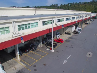Rua de acesso aos módulos e fachada de um bloco de galpões típico.