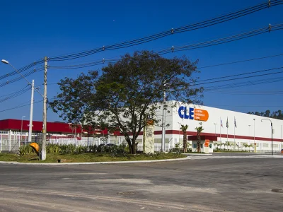 Fachada principal do condomínio com árvore na frente e céu azul.